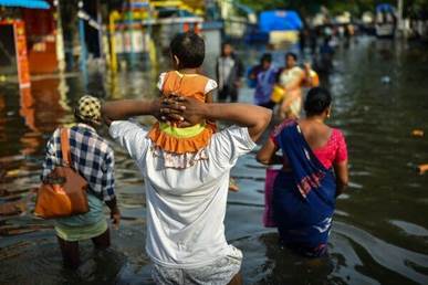 A father holding his child waded through a flooded neighborhood following heavy rains, in Chennai, India last year.
